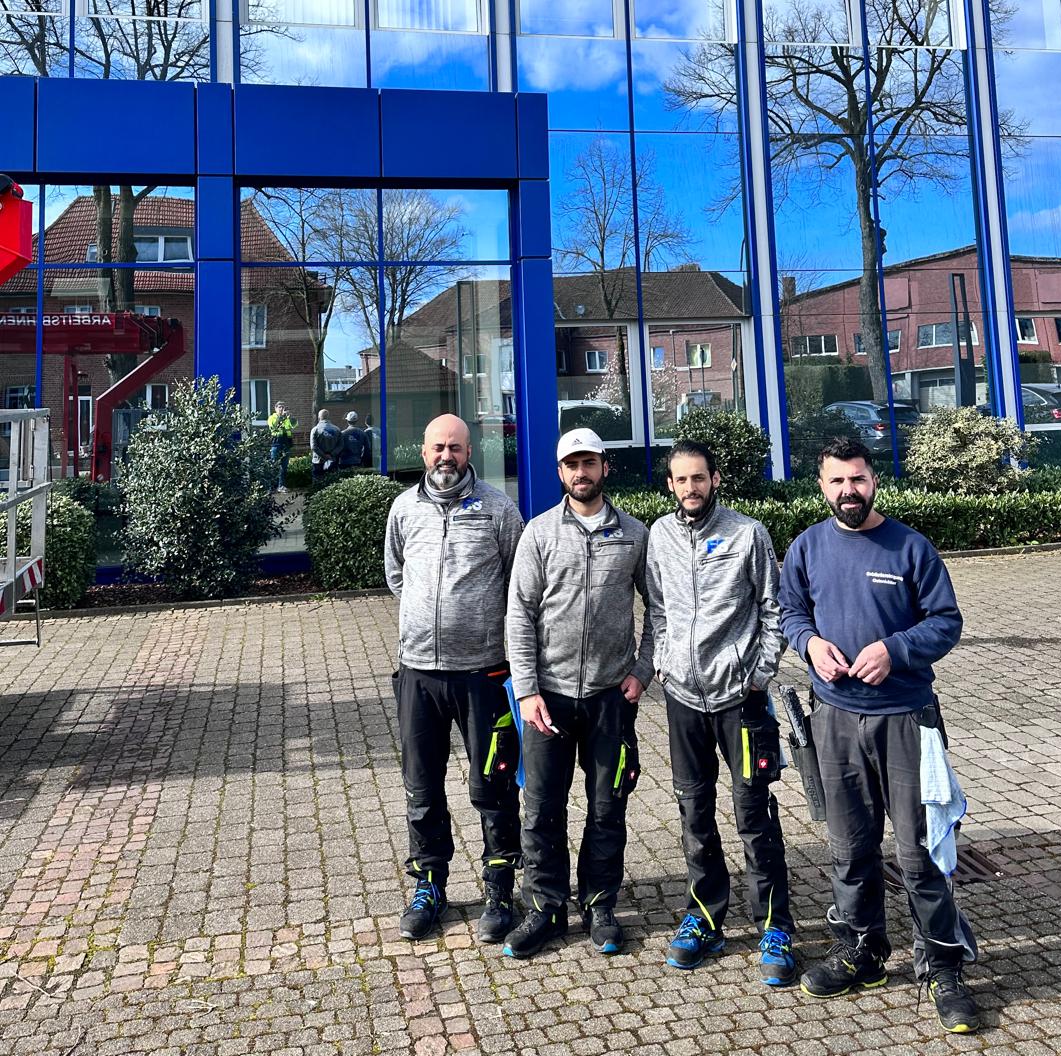 Team von ES-Gebäudereinigung vor einem gereinigten Glasgebäude